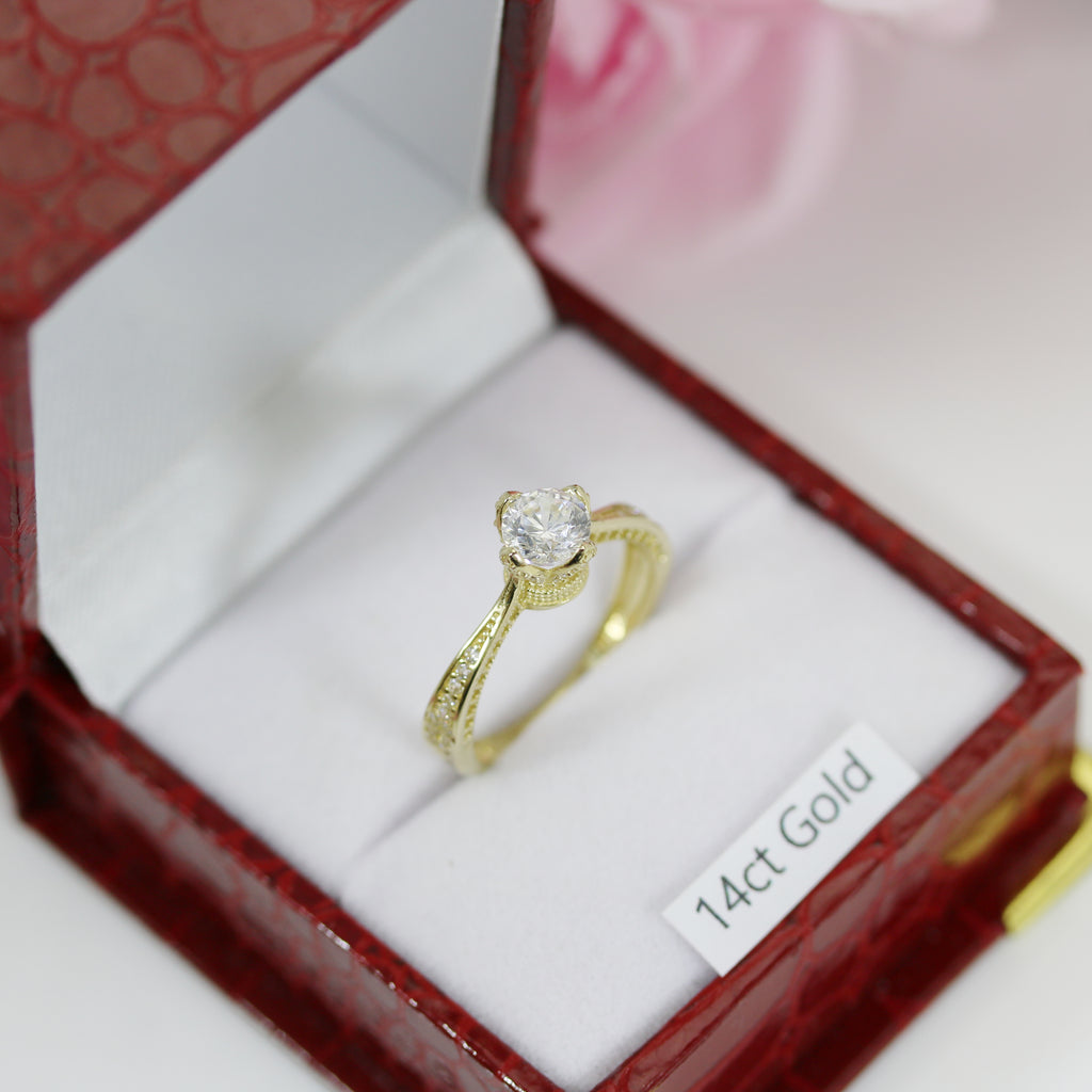 Profile view of 14ct gold CZ crown ring inside a red presentation box with floral background.