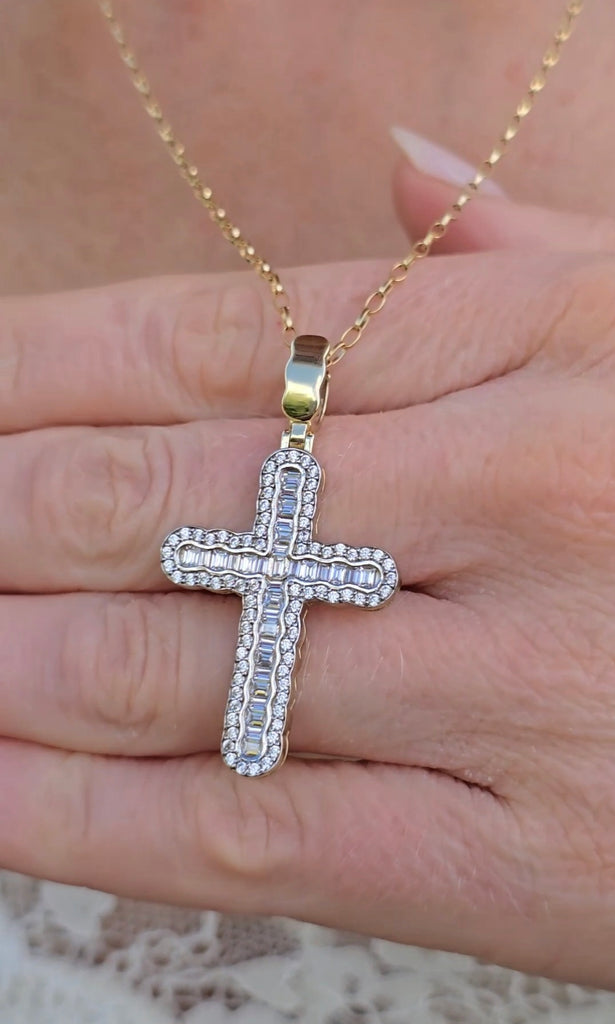 Front view of 9ct gold baguette and round CZ cross pendant held between fingers, showing stone detail.
Gleeson Jewellers 
