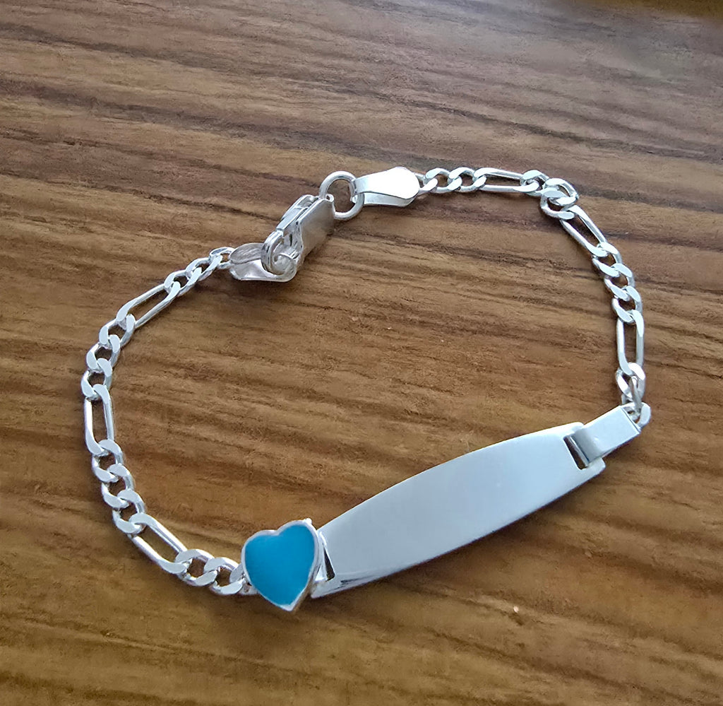 Silver baby id bracelet with a blue heart charm on a wooden surface