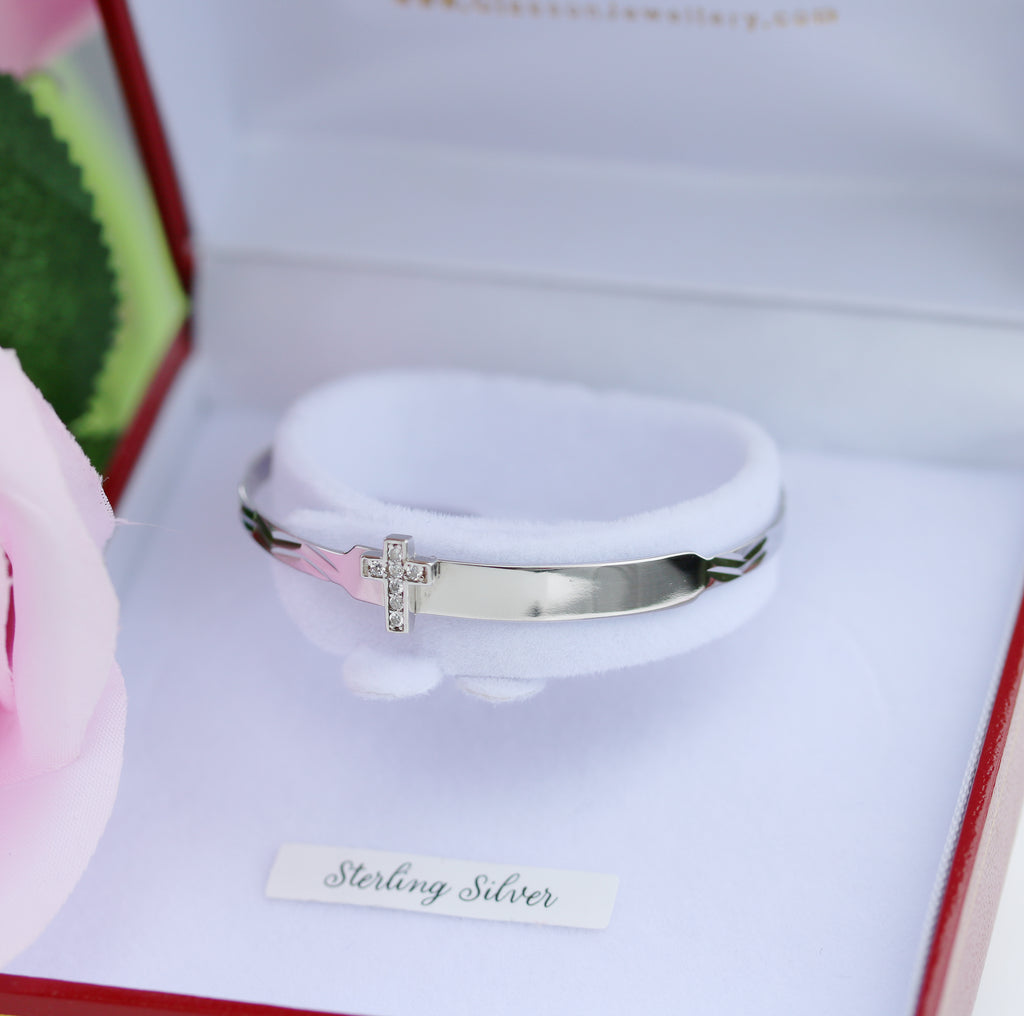 Sterling silver baby ID bangle with sparkling cross detail, displayed in a gleeson jewellers gift box.