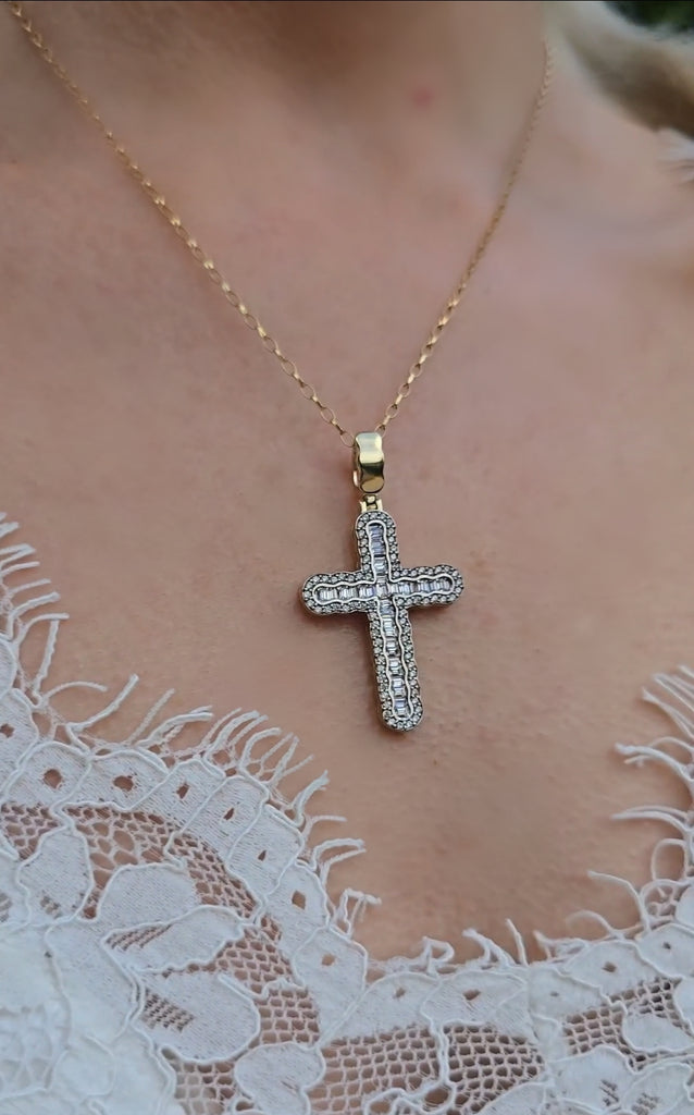 Close-up of 9ct gold cross pendant with baguette and round CZ stones on 24-inch Belcher chain, worn against lace top