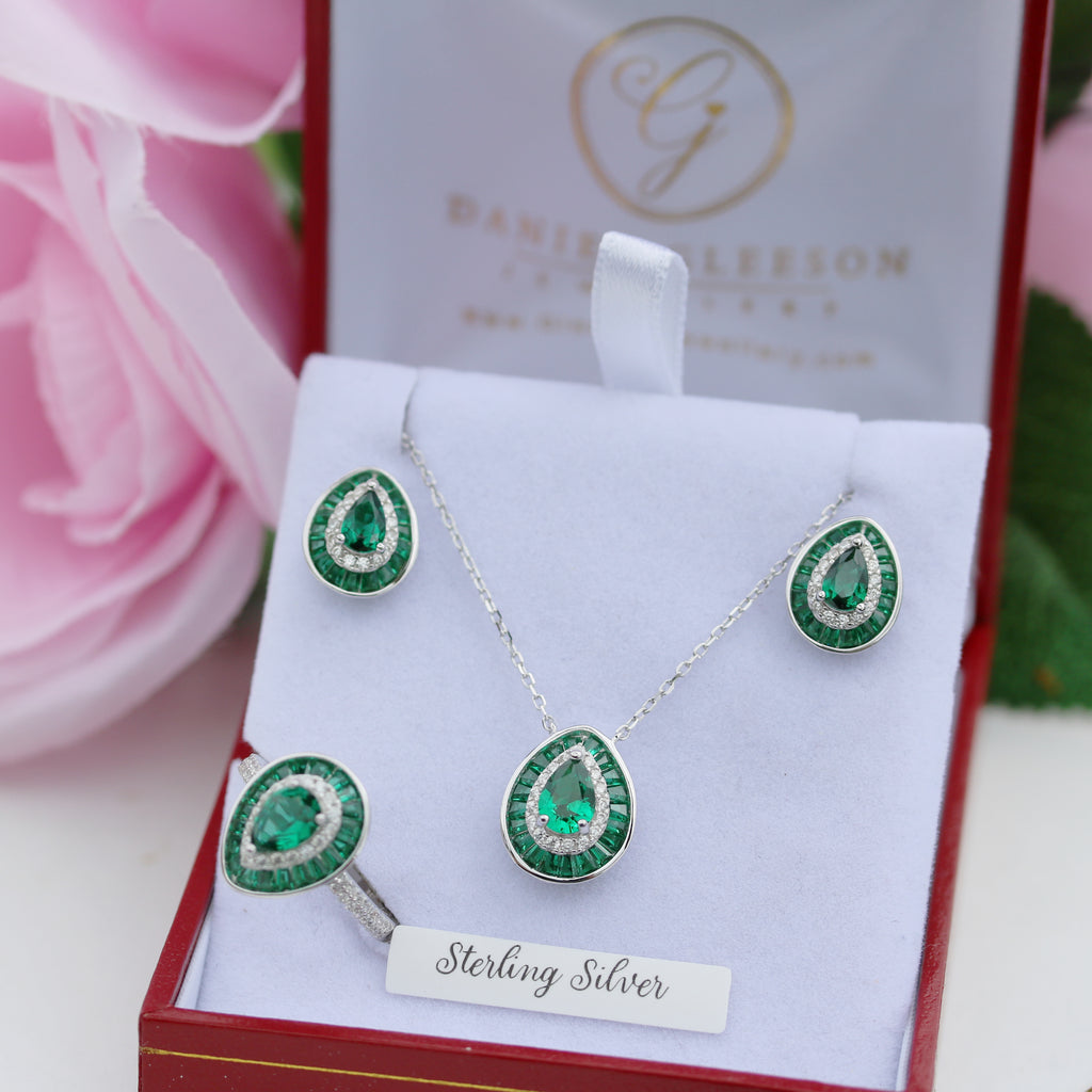 Green emerald gemstone jewellery set with 'Sterling Silver' label on a gleeson jewellers box with pink flowers in the background.