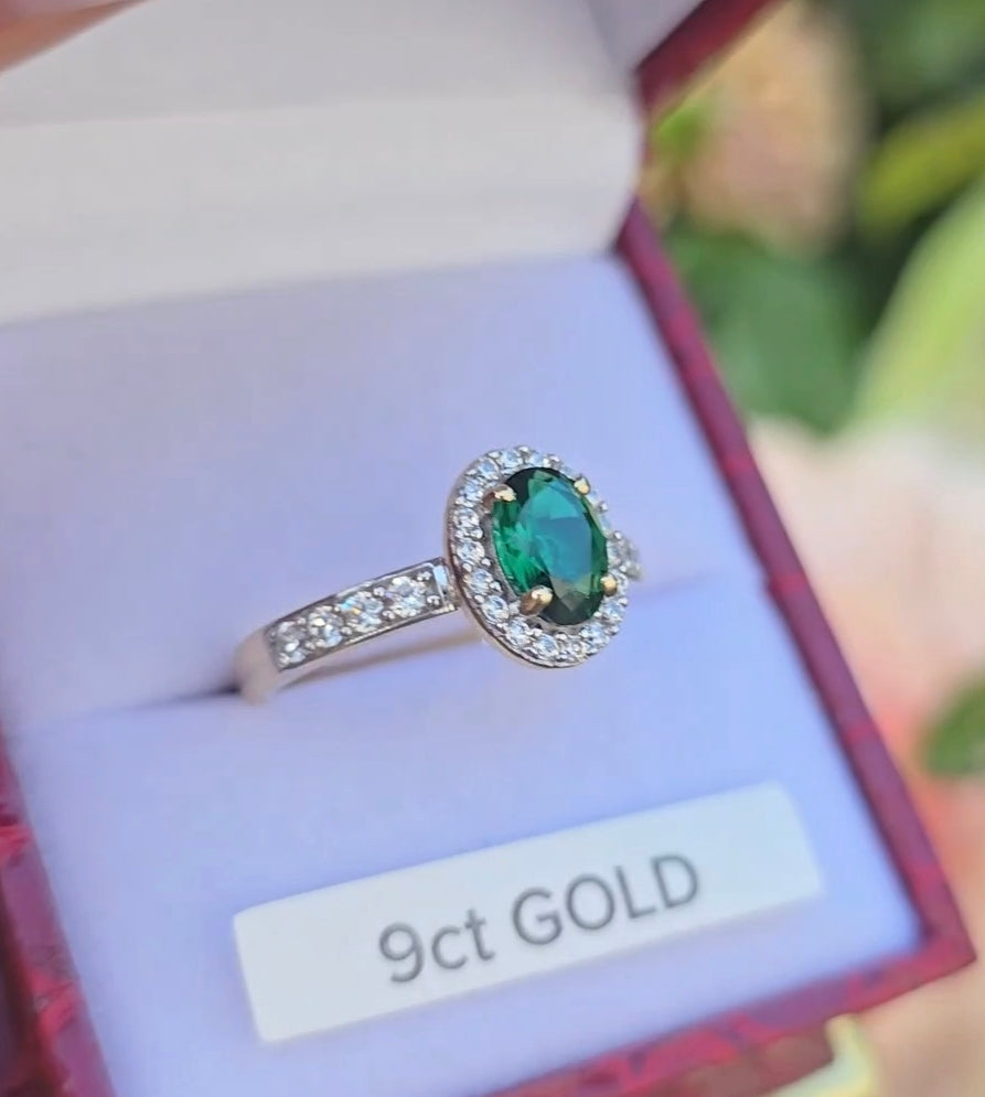Angled view of a 9ct gold emerald and cubic zirconia dress ring in a red jewellery box.