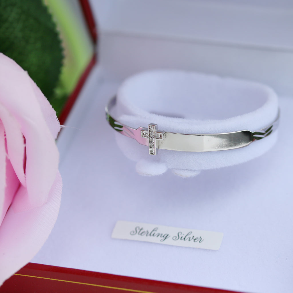 Side view of sterling silver baby bangle with cross design, available at Gleeson Jewellers.