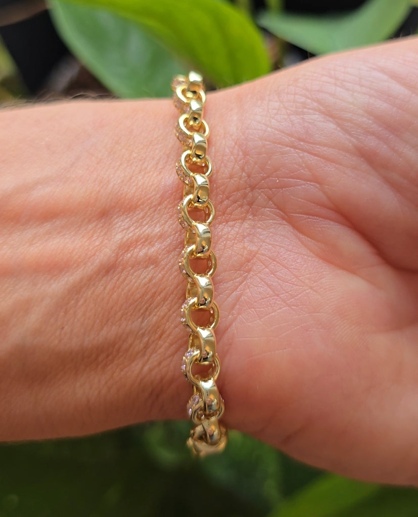 Gold-plated sterling silver patterned belcher link bracelet displayed on a wrist outdoors with green foliage in the background