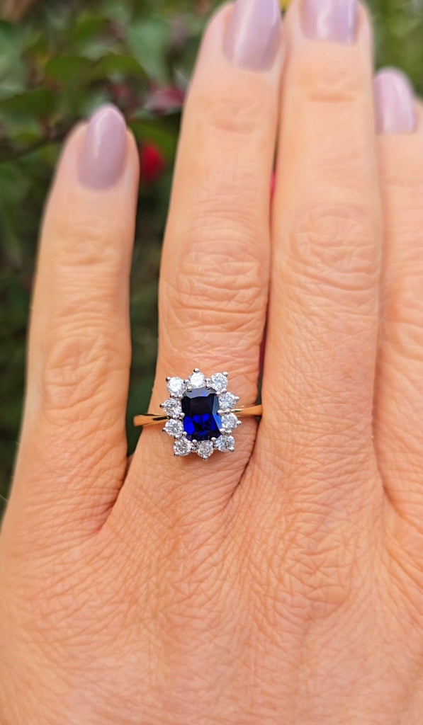 Natural light hand shot of the sapphire cluster ring, highlighting the radiant blue sapphire and halo design by Gleeson Jewellers.
