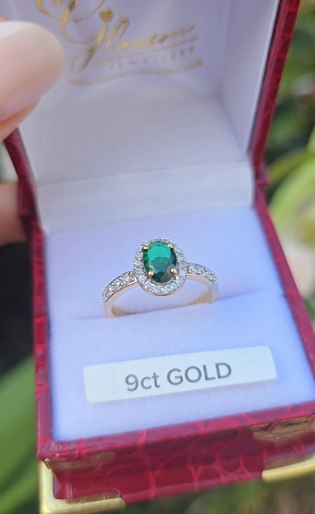 Front view of a 9ct gold emerald and cubic zirconia halo dress ring inside a jewellery box.