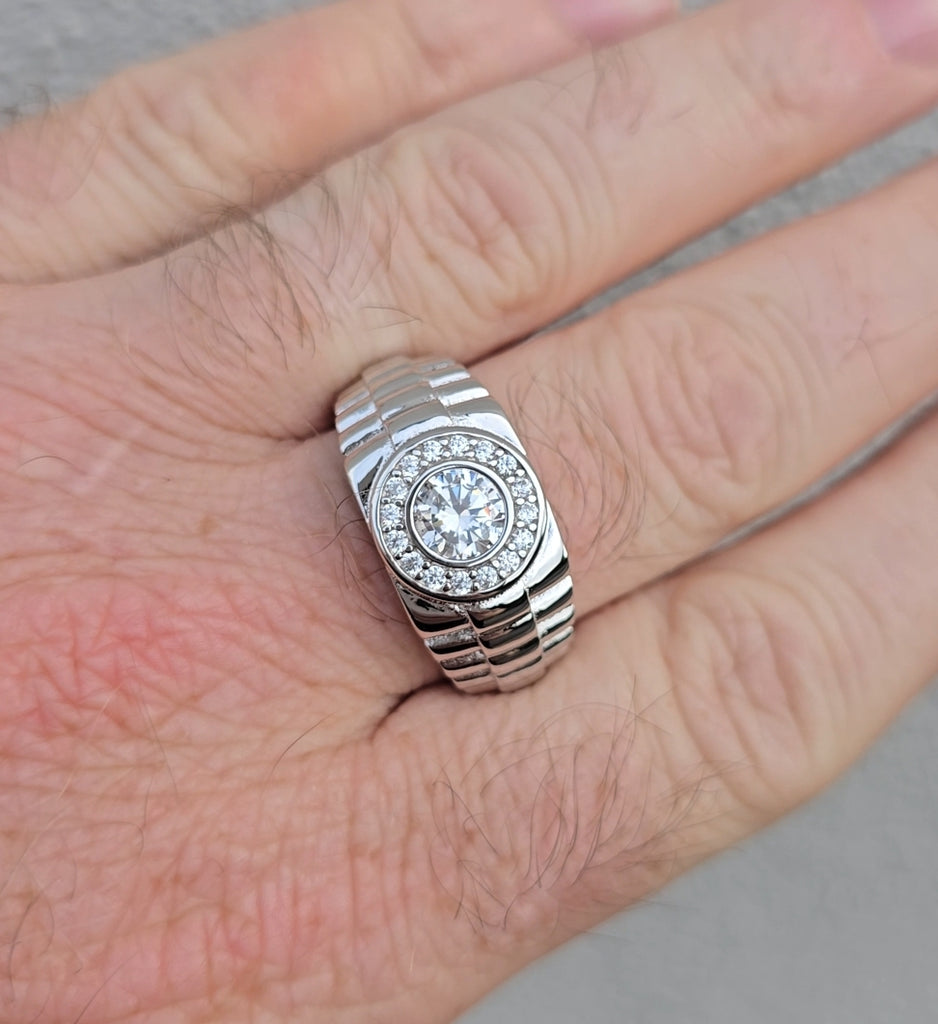 Front view of men's sterling silver ring featuring a round CZ center stone and halo, with Rolex-style brickwork band, worn on finger. available online from gleeson jewellers 
