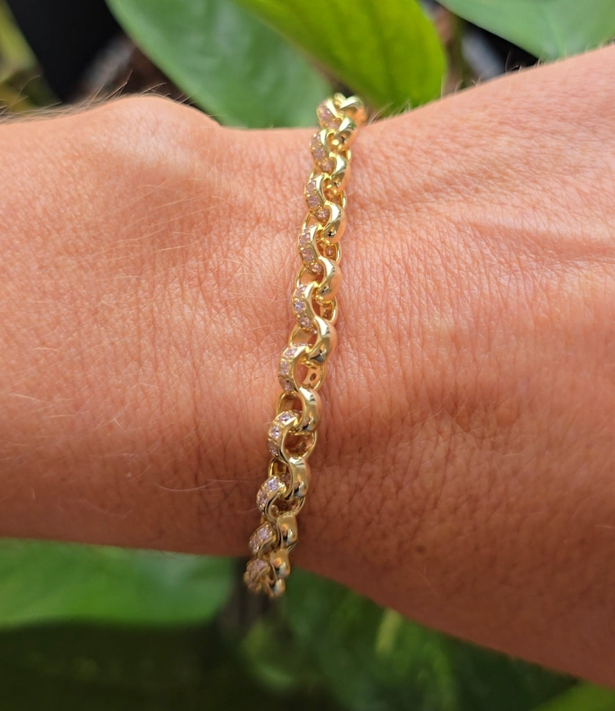 Close-up of gold-plated sterling silver patterned belcher link bracelet on a person’s wrist, photographed outside