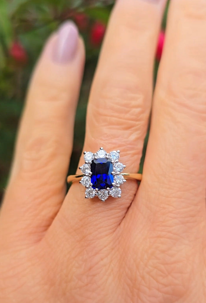 Natural light hand shot of the sapphire cluster ring, highlighting the radiant blue sapphire and halo design by Gleeson Jewellers.
