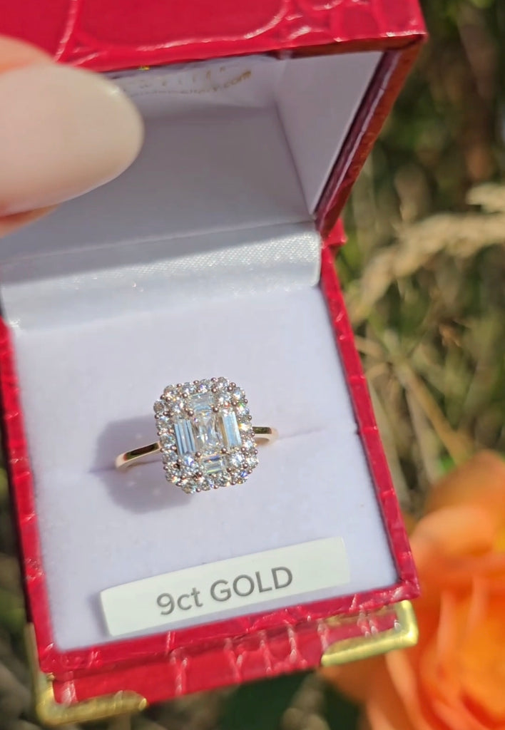 Close-up of a 9ct gold statement ring with a large emerald-cut cubic zirconia and halo setting, displayed in a red ring box.
Gleeson Jewellers 