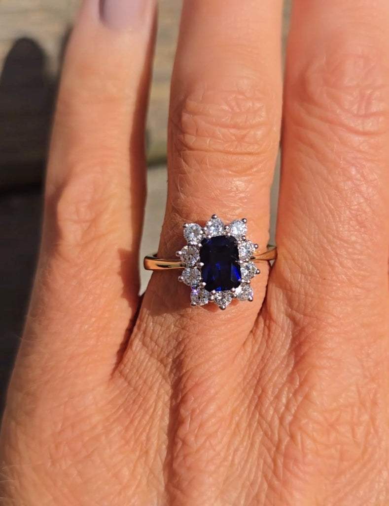 Close-up of a sapphire and cubic zirconia cluster ring on a hand, set in 9ct gold by Gleeson Jewellers.