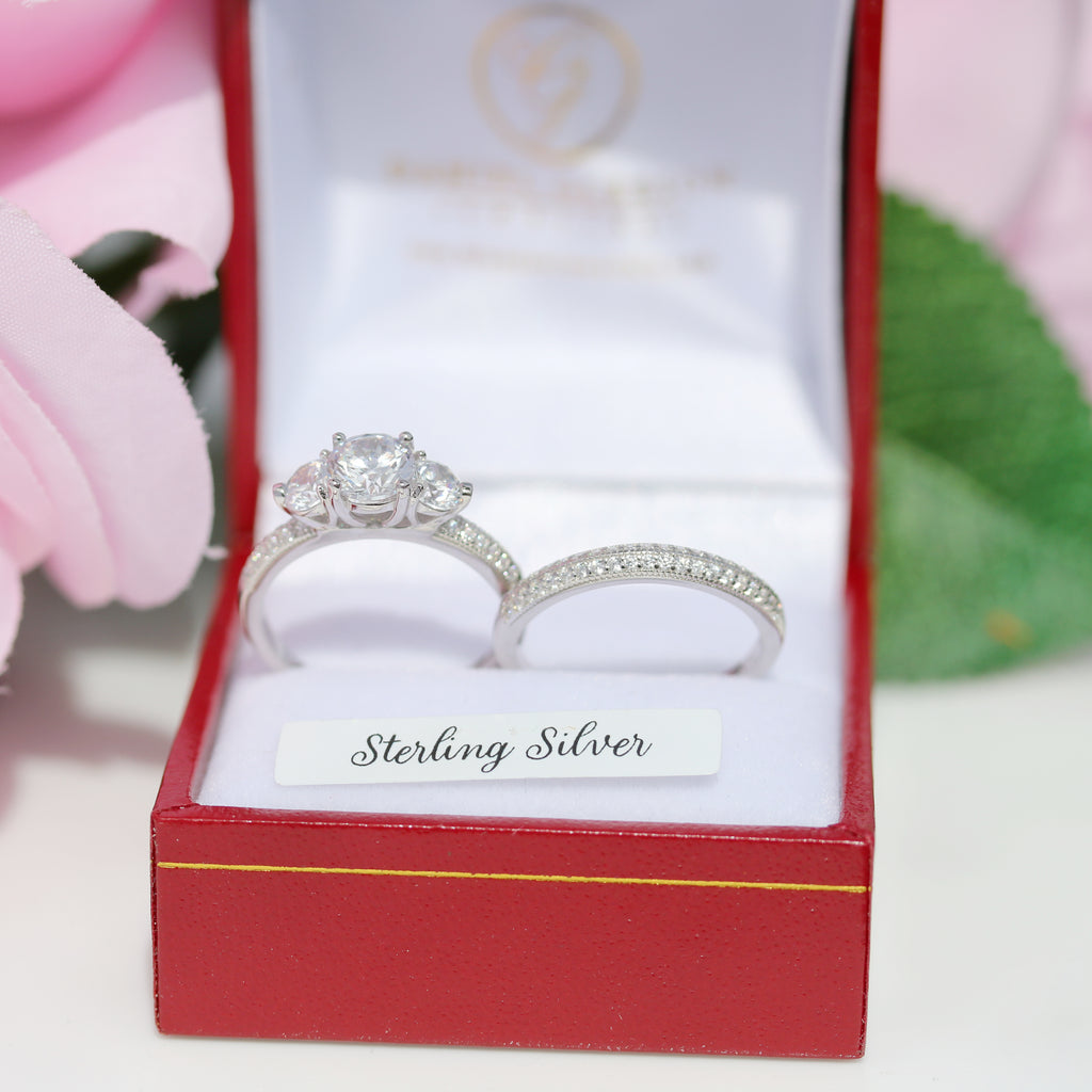 Sterling silver three-stone engagement ring set with cubic zirconia, presented in a red jewellery box against white and green floral background, from gleeson jewellers.