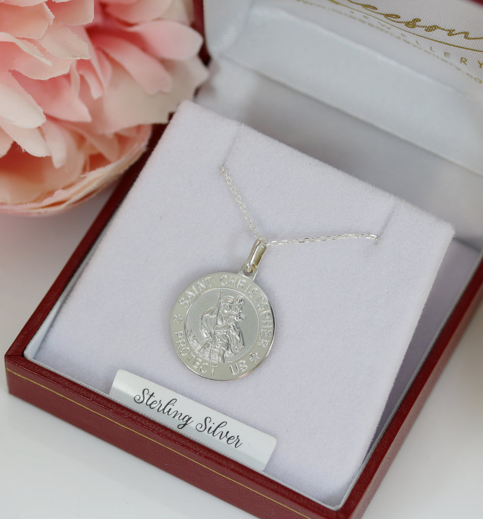 Sterling silver Saint Christopher medallion necklace presented in a red jewelry box with soft floral accents, perfect for gifting