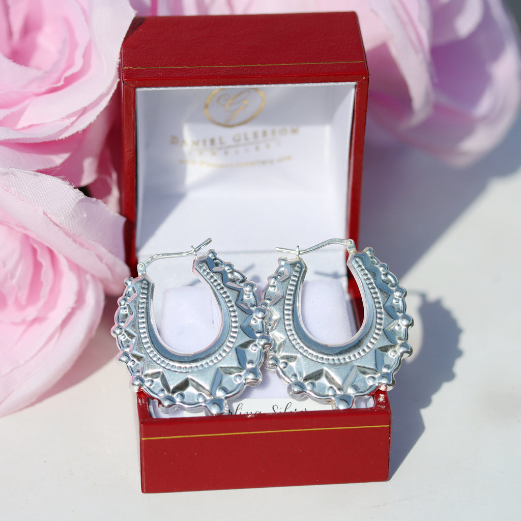 Gleeson Jewellers sterling silver spike creole earrings in a red gift box styled with soft pink flowers.