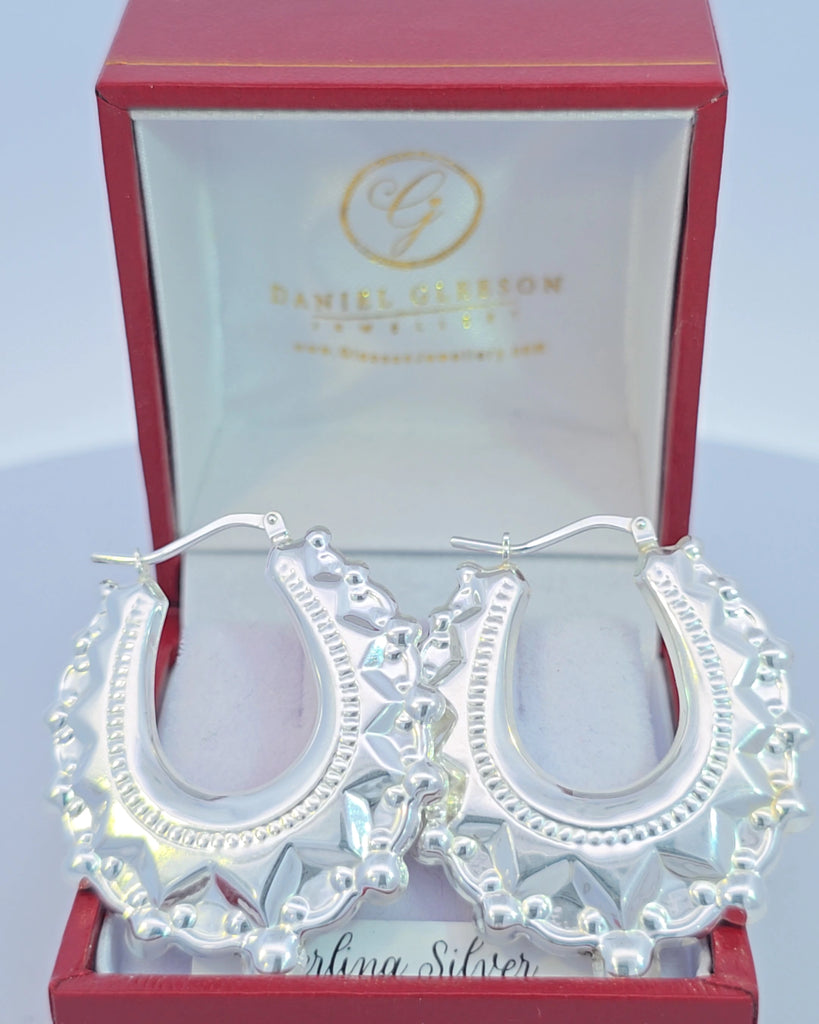 Front-facing sterling silver spike creole earrings from Gleeson Jewellers in red jewelry packaging.