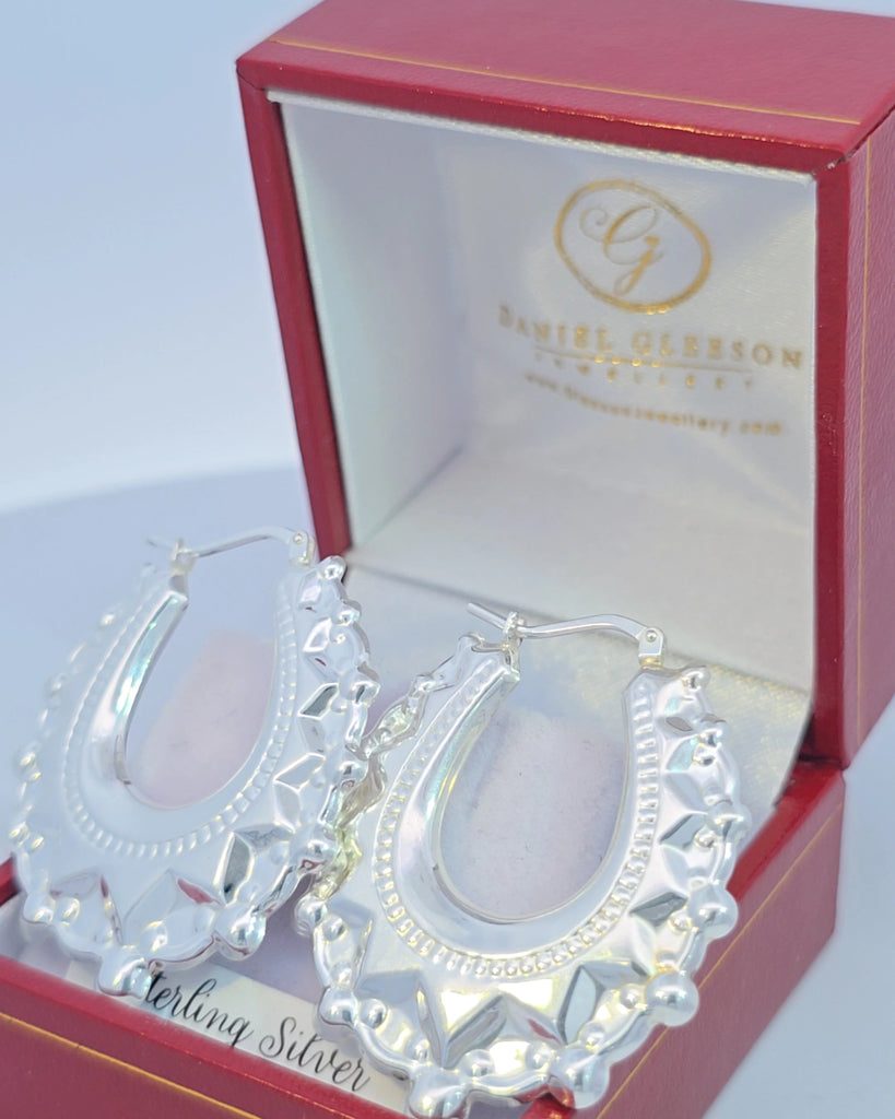 Shiny sterling silver creole earrings from Gleeson Jewellers displayed with branded packaging.