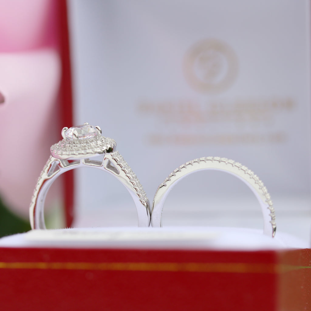 Close-up side view of sterling silver halo engagement ring with matching wedding band in a red box.