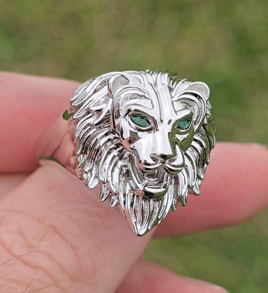 Close-up of sterling silver lion head ring with green CZ eyes, showing detailed mane and polished finish.
