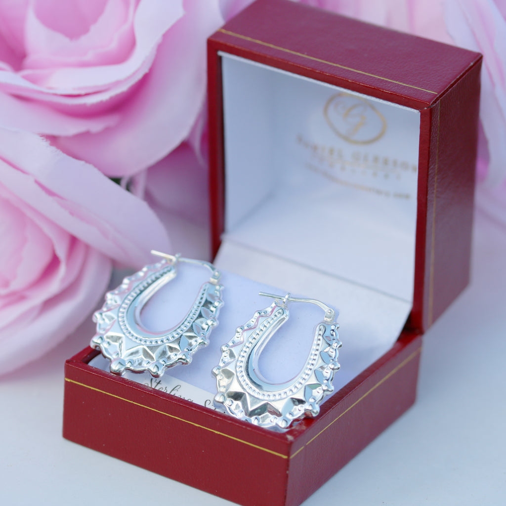 925 sterling silver oval spiked creole earrings by Gleeson Jewellers displayed in a red gift box with pink roses.