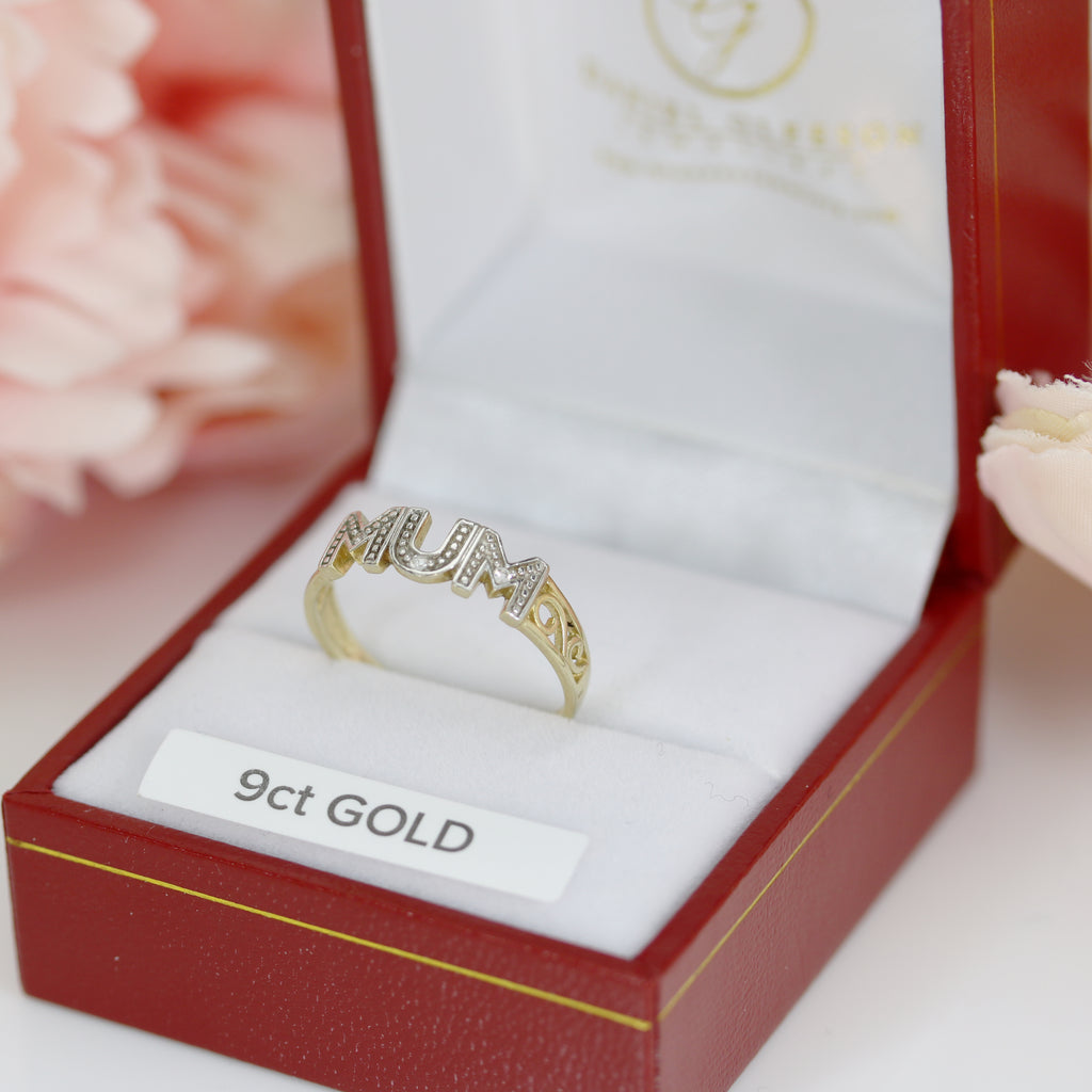 Beautifully crafted 9ct Gold Mum Ring with natural diamonds, presented in a jewelry box with soft floral accents in the background.