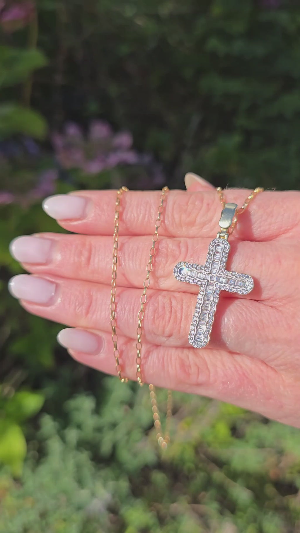 Natural light close-up of 9ct gold Gleeson Jewellers cross pendant with baguette and round CZ stones, gold chain visible above.