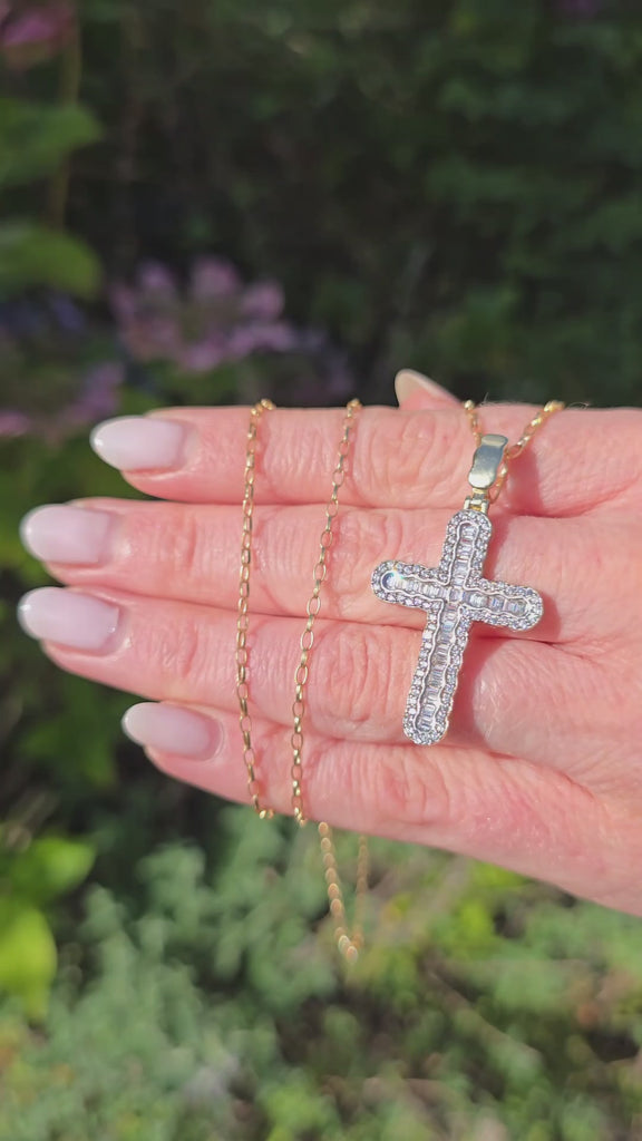 Natural light close-up of 9ct gold Gleeson Jewellers cross pendant with baguette and round CZ stones, gold chain visible above.
