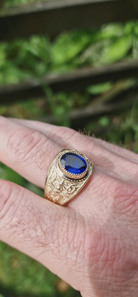 College ring with royal blue stone in 9ct gold displayed on mans hand
