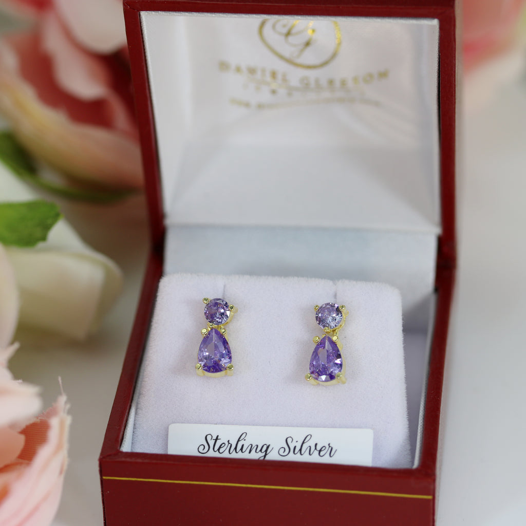 Sterling silver petite drop earrings featuring brilliant purple amethyst CZ stones, displayed in a classic gift box with a white velvet cushion