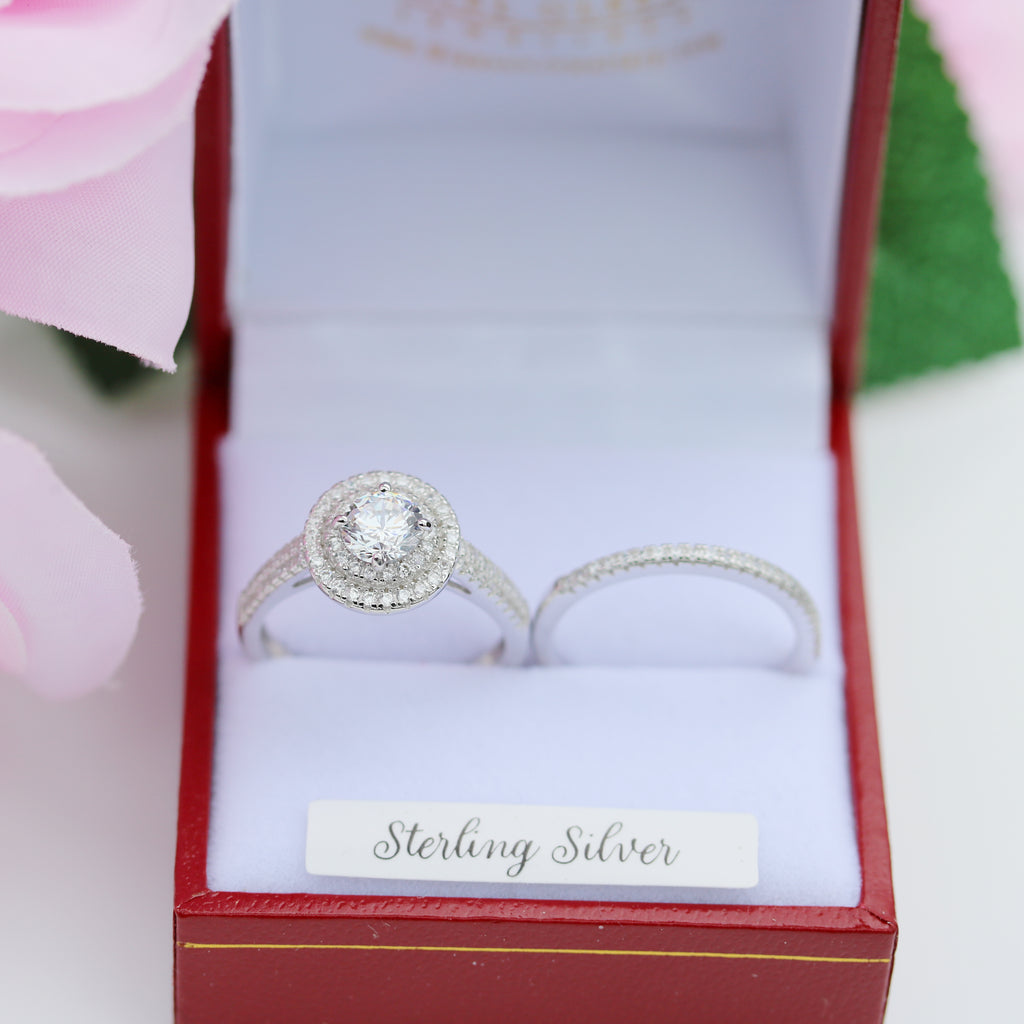Sterling silver halo engagement ring with matching pavé wedding band, displayed in a red Gleeson Jewellers box with pink rose accents.