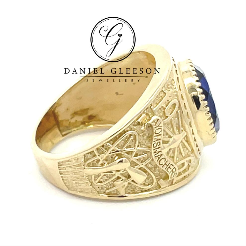 side profile college ring with detailed design on shoulders and shank of the ring and a beautiful royal blue stone in the middle supplied from Daniel Gleeson Jewellers